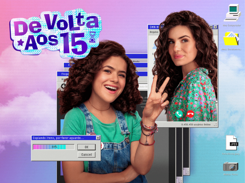 Poster da série "De volta aos 15". É como se fosse uma tela de computador, com o fundo apresentando o céu colorido em rosa, lilás e ciano, com nuvens. No centro, uma jovem branca de cabelo castanho cacheado, sorrindo e fazendo um 2 com a mão. Ela usa uma blusa verde-água e uma jardineira jeans. Em uma janelinha ao lado, uma mulher um pouco mais velha, mas com exatamente as mesmas características da outra, só que a blusa possui florzinhas. No canto, alguns aplicativos, e no topo esquerdo o nome da série como um adesivo.